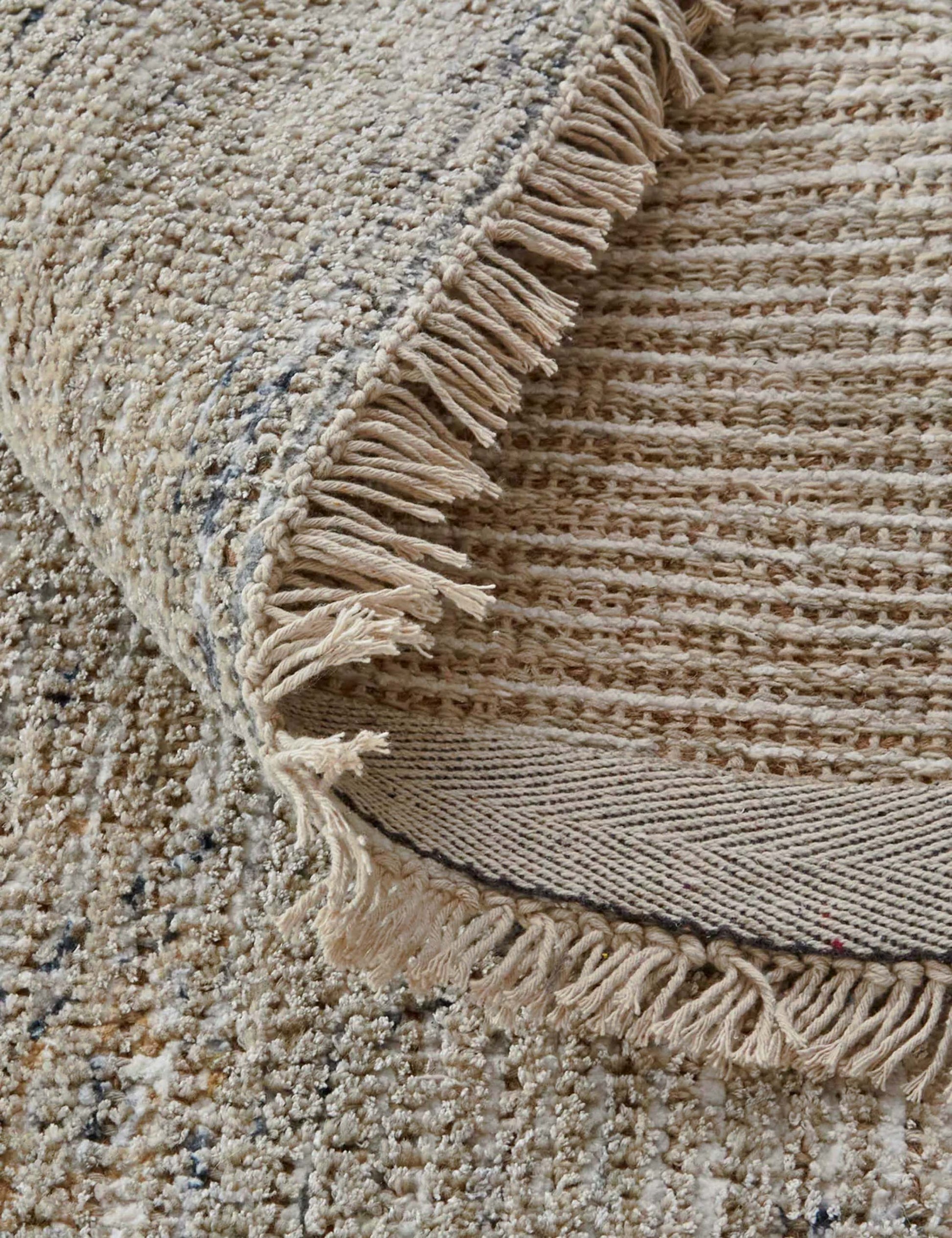 #color::sand #size::2--x-3- #size::3-6--x-5-6- #size::5--x-7-6- #size::7-6--x-9-6- #size::9--x-12- #size::10--x-14- | Close-up of the natural fiber fabric and fringed ends on the Ismenia distressed persian rug