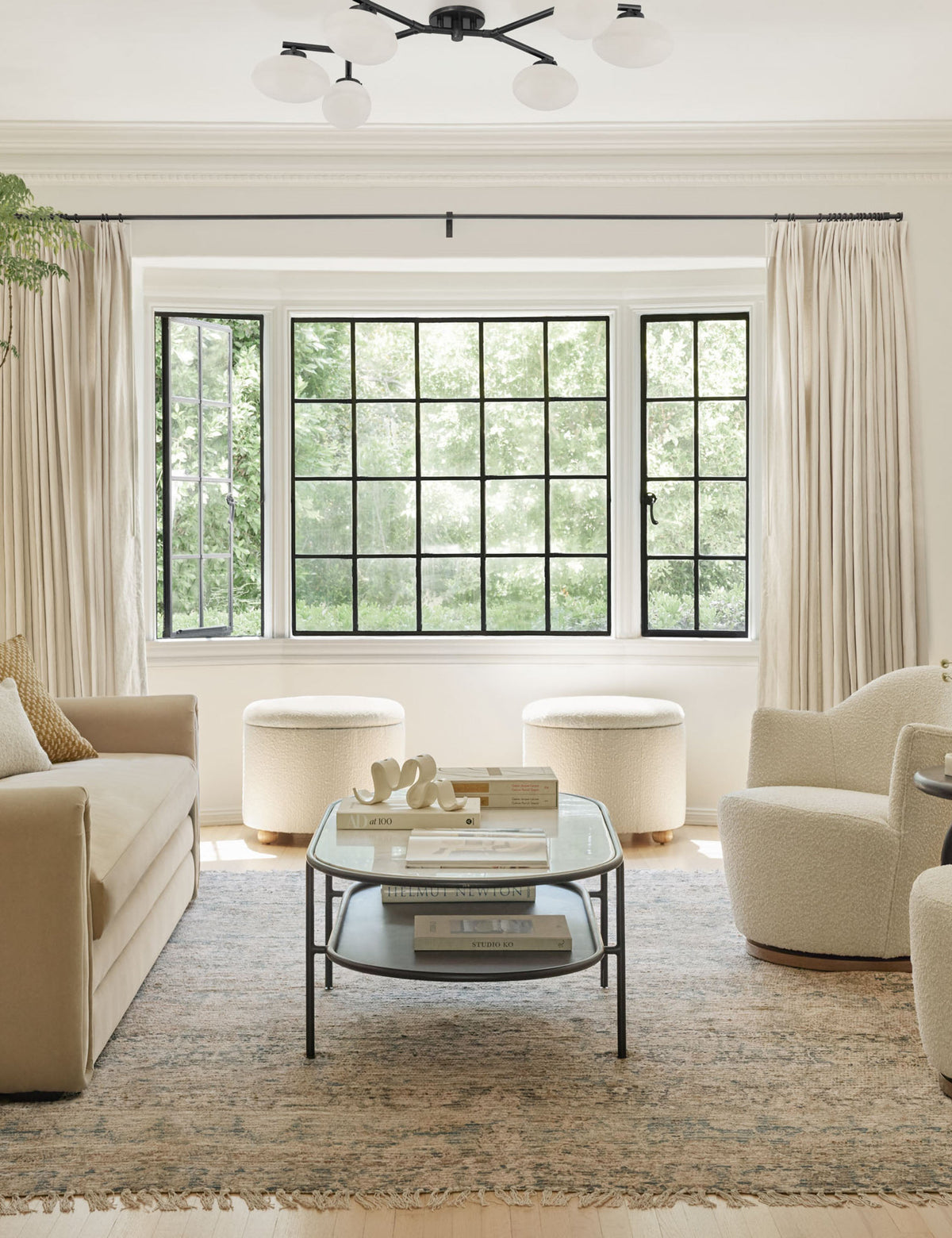 #color::antique-bronze #size::6-light | The Solange antique bronze branching 6-light semi flush mount light is mounted in a living room with two white boucle accent chairs, a persian rug, and a beige linen sofa