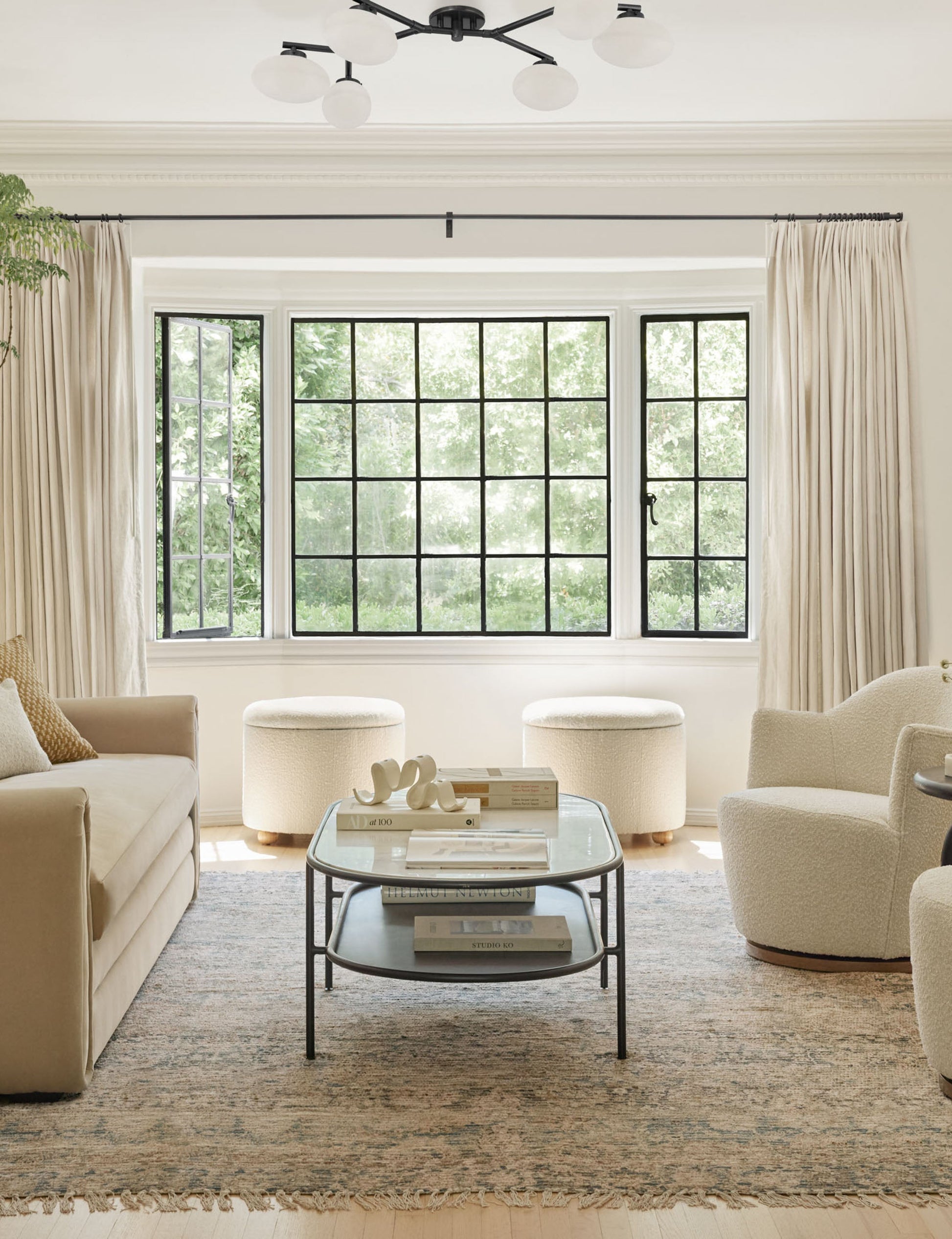 #color::antique-bronze #size::6-light | The Solange antique bronze branching 6-light semi flush mount light is mounted in a living room with two white boucle accent chairs, a persian rug, and a beige linen sofa