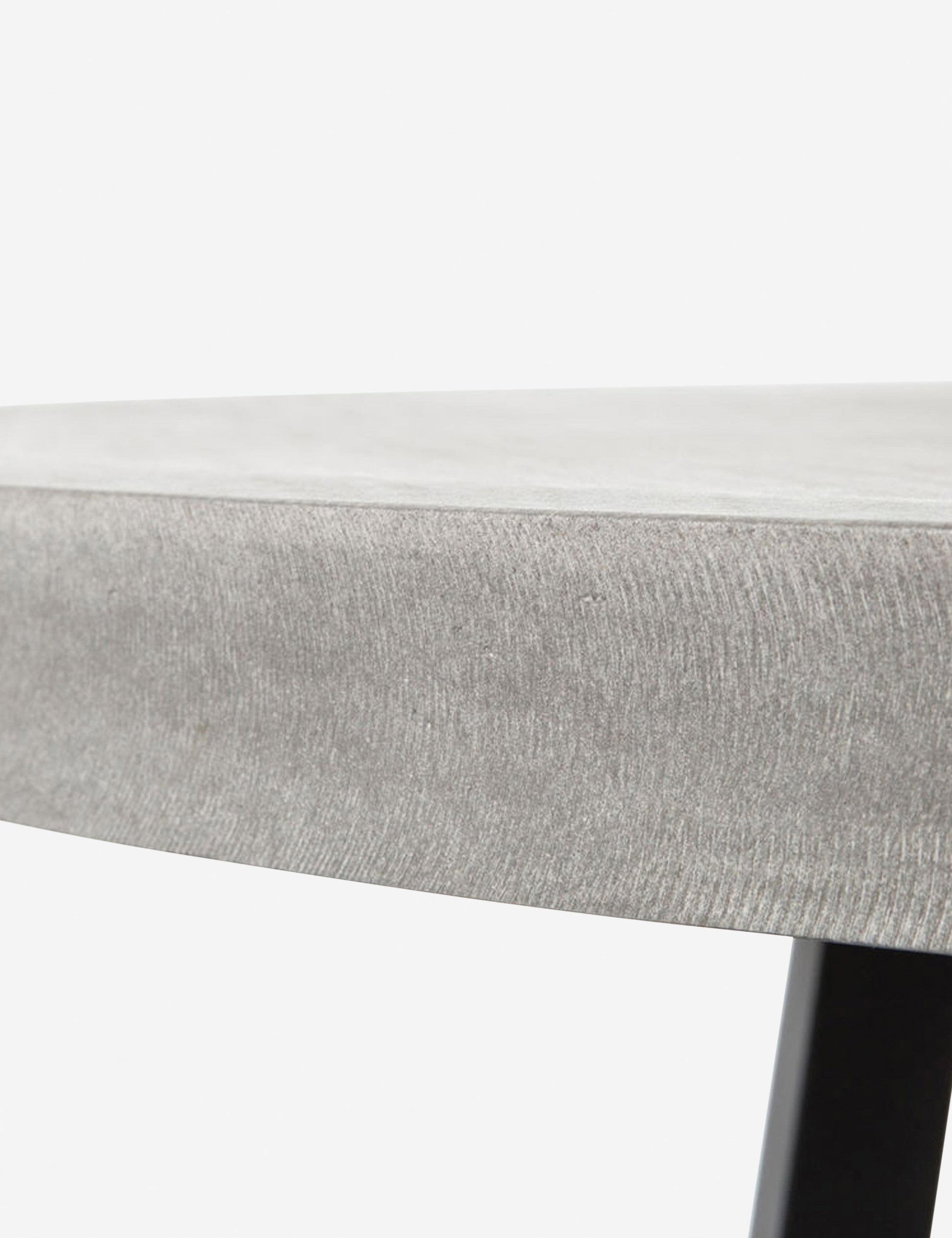 | Close-up view of the side of the tabletop on the Agatha indoor and outdoor dining table with lavastone top and black iron base