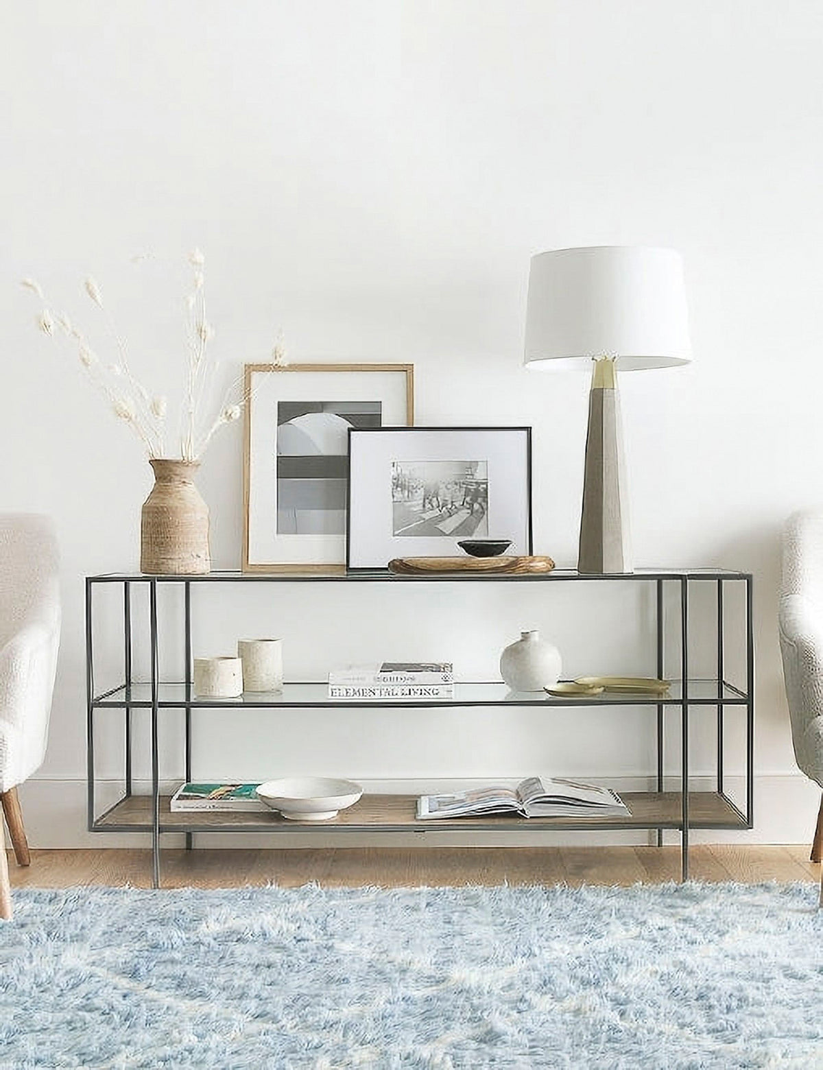 | The Asher console table filled with decorative objects sits against a white wall in a room with a blue rug