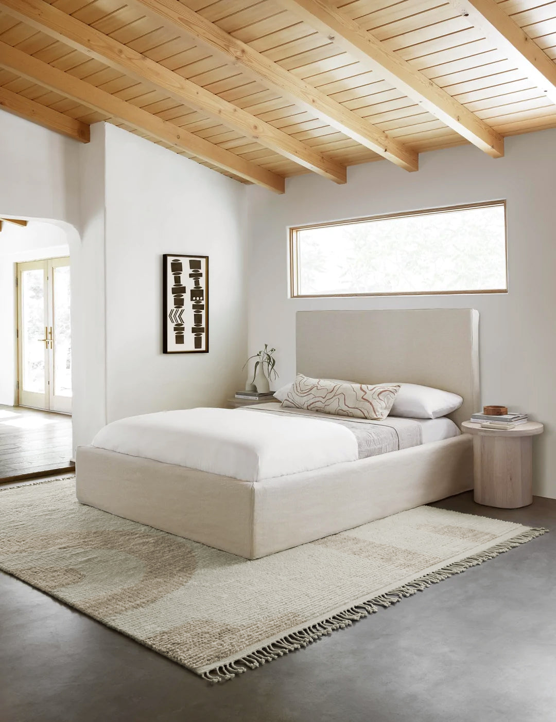 #size::2-6--x-8- #size::6--x-9- #size::8--x-10- #size::9--x-12- #size::10--x-14- #size::12--x-15- | The Nomad neutral-toned geometric floor rug with subtle ribbed design by Élan Byrd lays in a bedroom with a geometric black and white wall art, a natural linen framed queen bed, and white-washed wooden nightstands