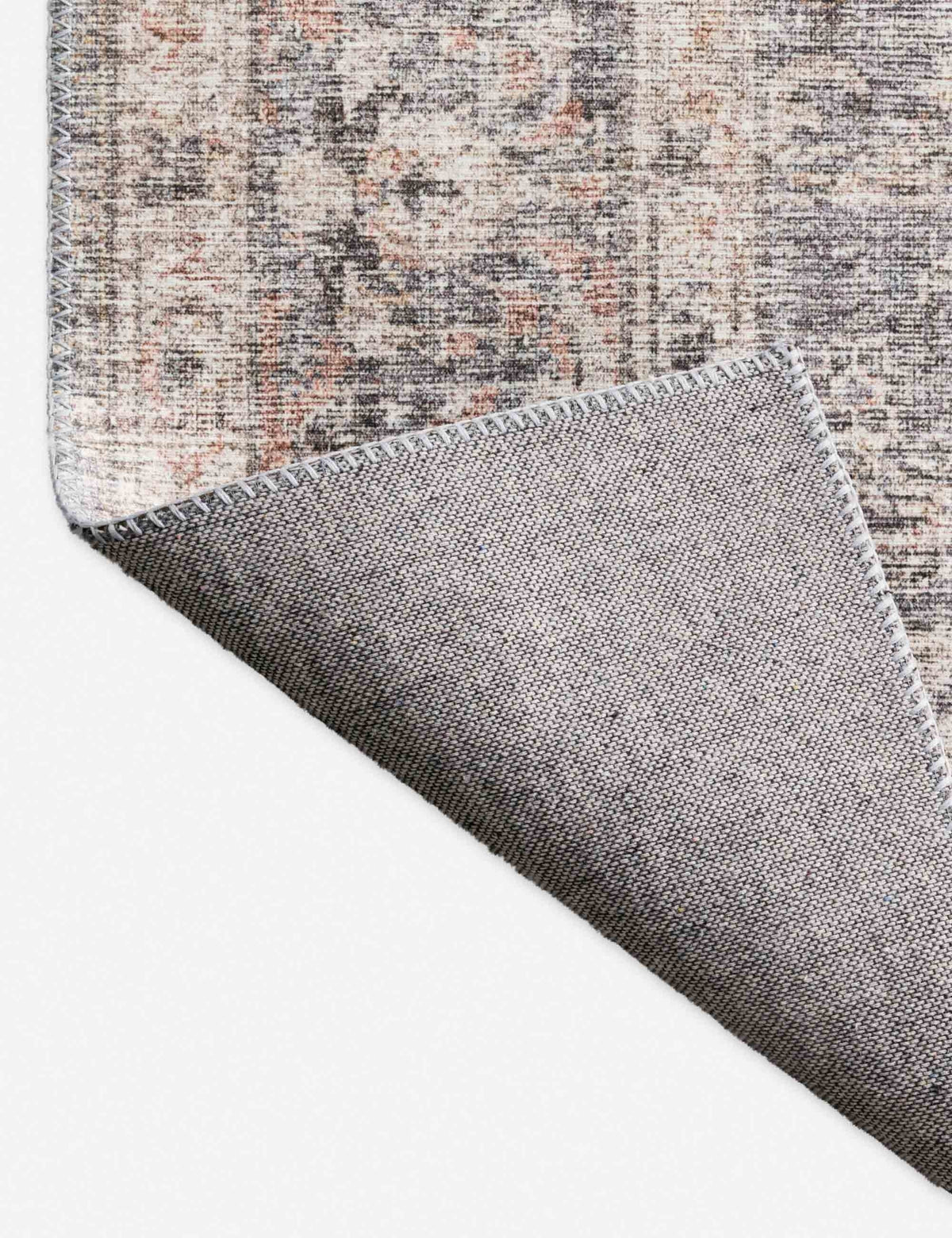 #color::grey-and-apricot #size::2-3--x-3-9- #size::2-6--x-7-6- #size::3-6--x-5-6- #size::5--x-7-6- #size::7-6--x-9-6- #size::9--x-12- | Close-up of the corner of the Roze grey and apricot power-loomed rug with medallion patterns with the bottom folded over