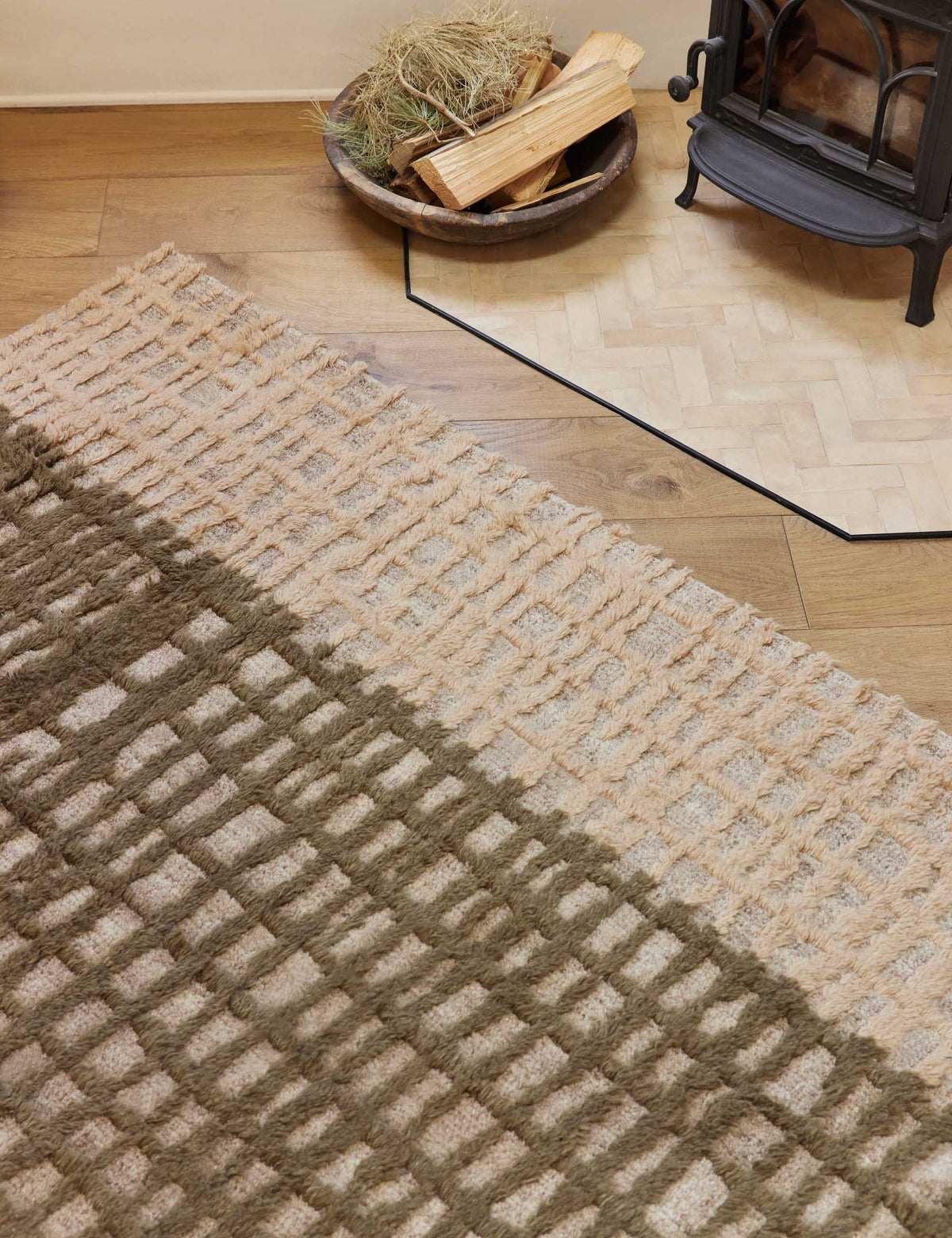 #size::6--x-9- #size::8--x-10- #size::9--x-12- #size::10--x-14- #size::12--x-15- | Close-up of the Terra handcrafted textured multicolored floor rug by Élan Byrd sitting in a room with a wood-burning fireplace atop hardwood floors