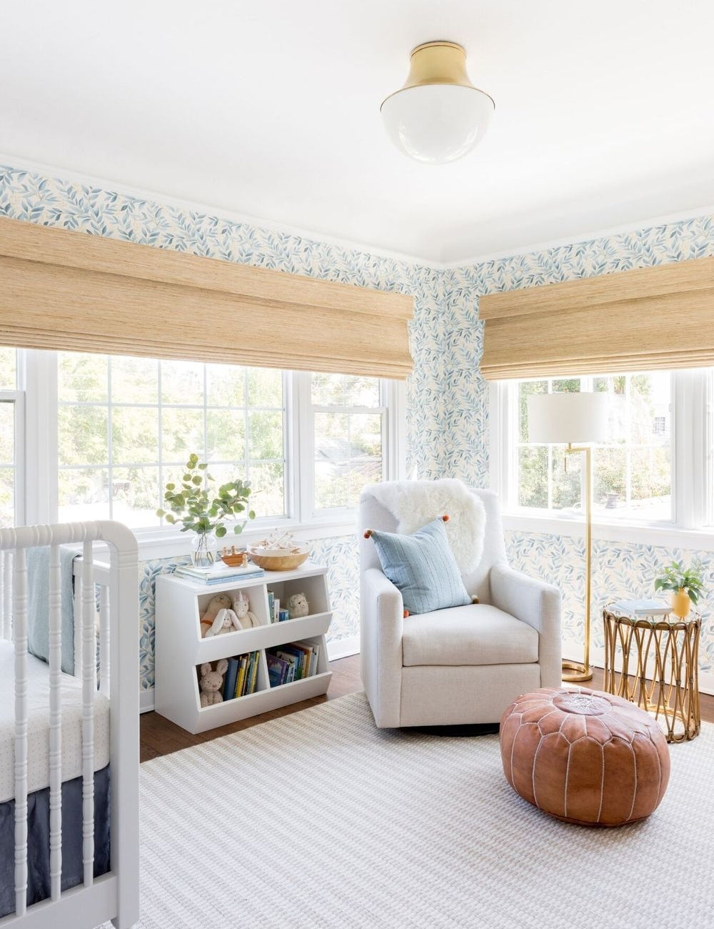 #showall::39489938817123 | The Randi curved brass Flush Mount Light with domed glass cover is mounted in a nursery with floral wallpaper, white furniture, and a leather ottoman